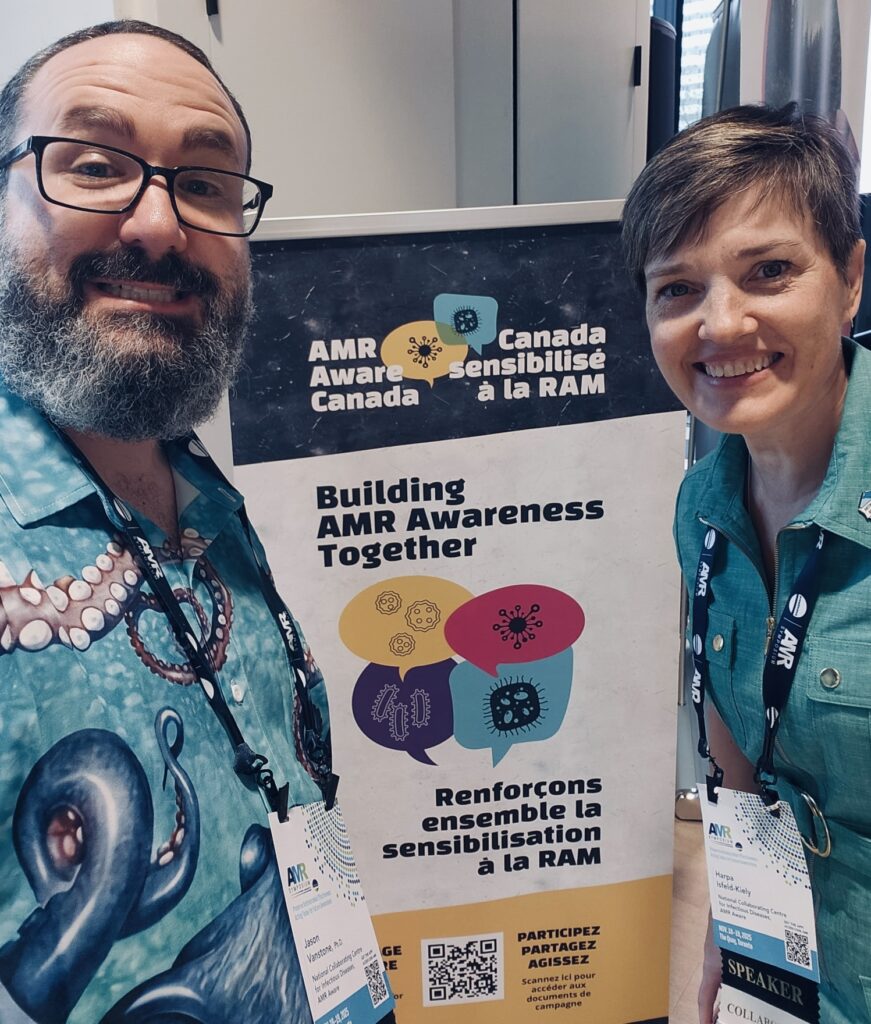 Photo of two representatives of the AMR Aware Canada collaboration standing by the campaign banner that says 'Building AMR Awareness Together'.