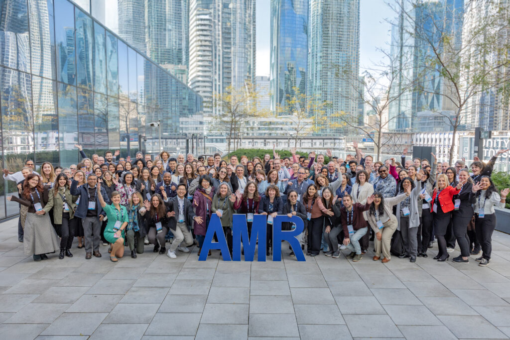 Group photo of participants at the AMR Symposium, posing with the letters 'AMR'. Toronto's downtown is seen in the background.